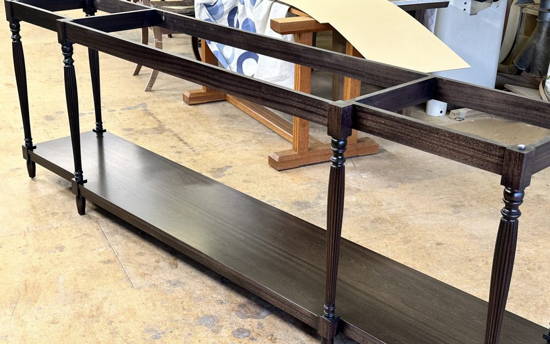 Bespoke traditional dark wood console table frame with turned legs under construction in a custom furniture design workshop.